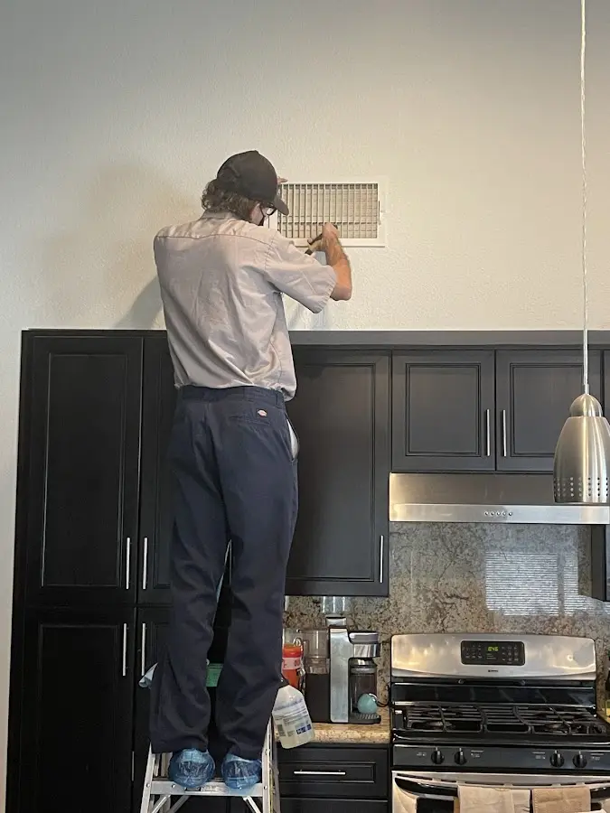 Technician inspecting an air vent during HVAC service in Dallas